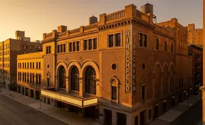 Golden hour light illuminates the Hirschfeld Theatre on a city street.