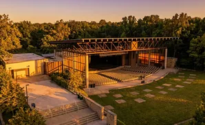 An outdoor amphitheater with tiered seating and a covered stage at sunset.