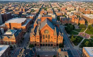 Aerial view of a historic brick concert hall and surrounding urban cityscape at golden hour.