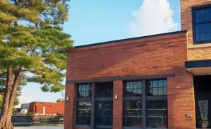 Exterior of a brick building with large windows and a tree.