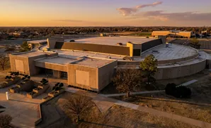 Aerial view of a large, circular building with a flat roof at sunset.