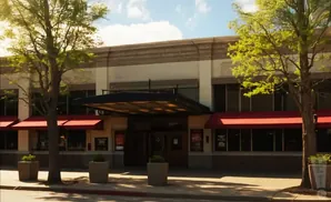 Exterior of a theater with red awnings and trees.