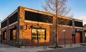 A brick building with stone accents and large windows bathed in golden sunlight.
