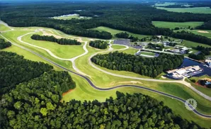 Aerial view of a winding race track through lush green forests and fields.
