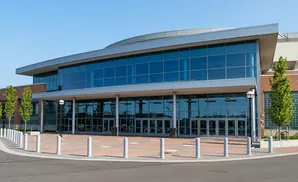 Modern building with large glass windows and entrance, flanked by trees.