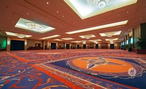 An empty, grand ballroom with ornate carpets and chandeliers.