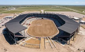 Aerial view of a rodeo arena with grandstands and a dirt arena.