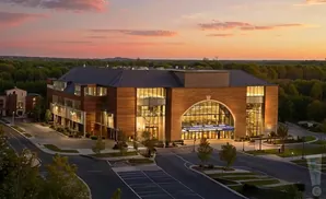 Modern building with large arched windows and wood accents at sunset.