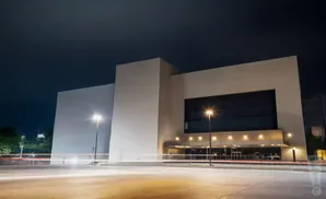 Modern building at night with light trails from cars on the road.