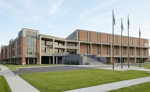 Modern brick and concrete building with large windows and flags.