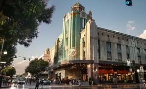 Art Deco building with a unique green copper facade and illuminated signage on a sunny day.