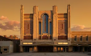 Art deco theater facade with ornate tilework and arched windows at sunset.