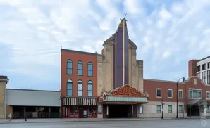 Exterior of an old movie theater with a marquee and brick buildings.