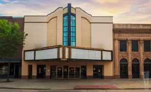 An old-fashioned movie theater with a marquee and ornate facade under a sunset sky.