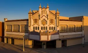 An ornate theater facade bathed in warm sunset light, featuring detailed gold accents and a marquee.