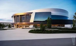 Modern circular building with glass facade and concrete plaza.