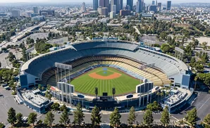 Aerial view of Dodger Stadium in Los Angeles, showing the baseball field and surrounding parking lots with the city skyline in the background.