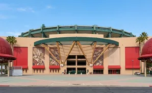 Exterior of a baseball stadium with red domes, beige walls, and abstract art.