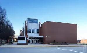 A modern building with a brick facade and a glass-windowed entrance under a clear blue sky.