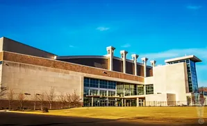 Modern convention center with large glass windows and light-colored stone facade under a clear blue sky.