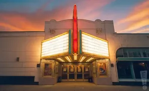 Marquee of a vintage theater at sunset, illuminated with gold and red lights.