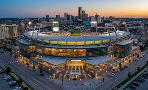 Aerial view of a baseball stadium at dusk with a city skyline in the background.