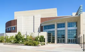 Modern building with large glass windows and brick accents, set against a clear blue sky.