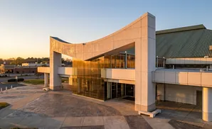 Modern building with curved architectural elements and golden glass facade, bathed in warm sunset light.