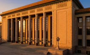 Grand building with large columns and ornate details bathed in warm sunlight.