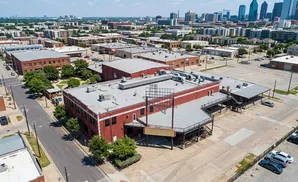 Aerial view of a red brick building with a large Texas-shaped sign and a marquee, surrounded by parking lots and trees.