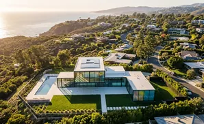 Modern glass house with pool overlooks the ocean and lush hillside homes.