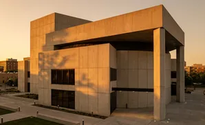 Modern concrete building with large windows bathed in golden hour sunlight.