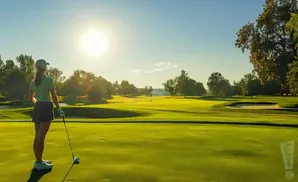 Golfer on a sunny golf course with trees and sand traps.