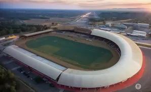 Aerial view of a horseshoe-shaped stadium with a green field and bleachers, set against a twilight sky.