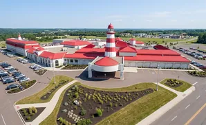 Aerial view of a casino with a red and white lighthouse, red roofs, and large parking lots.
