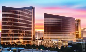 Two modern buildings with illuminated horizontal lines against a colorful sunset sky.