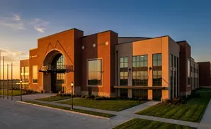 A modern brick and tan building with large windows at sunset.