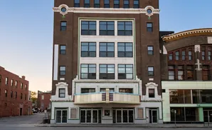 Exterior of an old theater with a marquee, brick facade, and large windows.