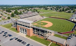 Aerial view of a baseball stadium with a diamond-shaped field and tiered seating, surrounded by parking lots and residential areas.
