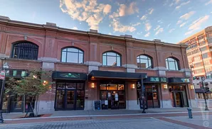 Exterior of a red brick building with arched windows, glass doors, and awnings.