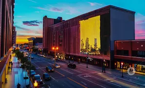 City street at sunset with a large mural on a brick building.