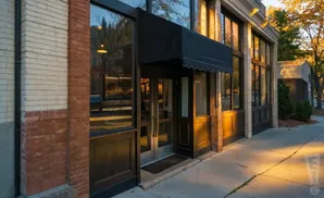 A storefront with a black awning over double glass doors and large windows, with brick and wood accents.
