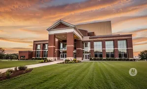 A large brick building with large windows under a dramatic sunset sky.