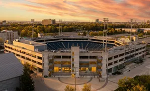 Aerial view of a stadium and parking garage at sunset.