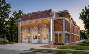 Modern brick building with arched doorways and slatted windows at dusk.