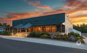 Modern building with large windows and a covered entrance at sunset.
