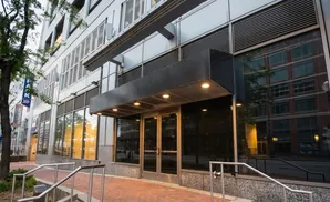 Modern building facade with glass doors and windows reflecting an adjacent brick building.