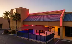 An outdoor patio with a red canopy and neon lights at dusk.