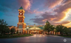 A grand brick building with a clock tower and green roof at sunset.