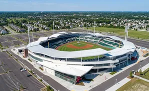 Aerial view of a modern baseball stadium with green seats, a baseball field, and surrounding neighborhoods.